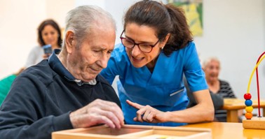 Memory care staff helping a gentleman with a puzzle